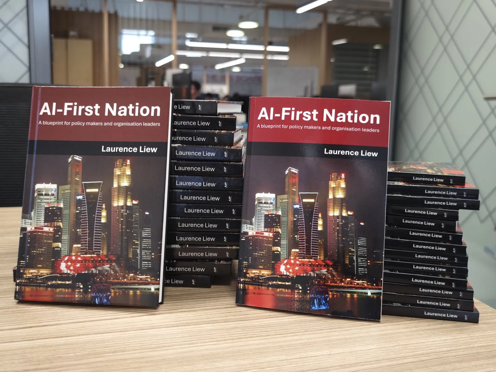 Freshly printed copies of the book AI-First Nation standing on a desk, the cover showing the Singapore skyline at night